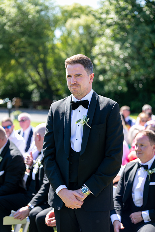 portrait of the groom waiting at the alter set outdoors in the sunshine