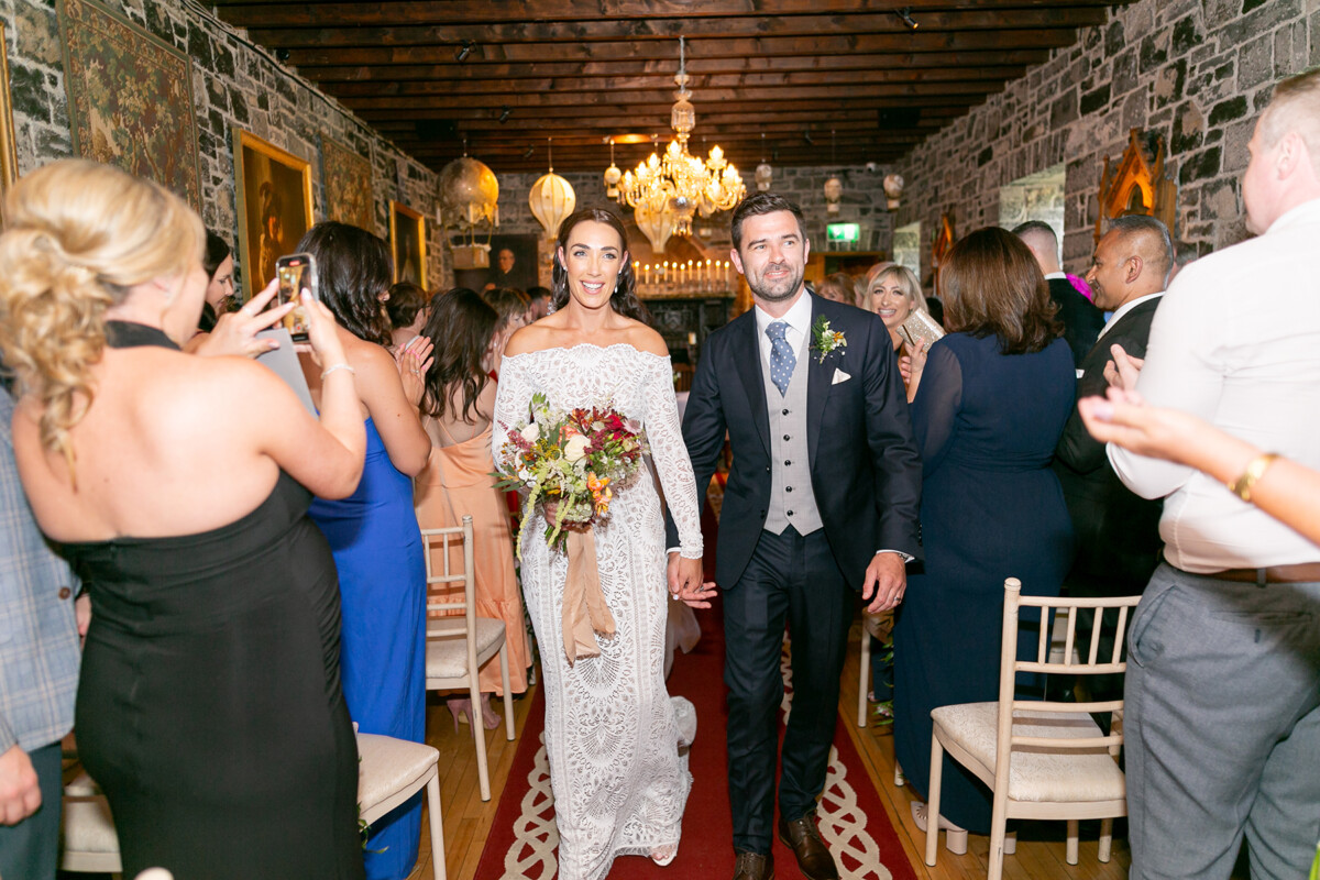 The bride and groom walk hand in hand back down the aisle togetherr making their exit from the wedding ceremony venue at Ballyseede castle hotel.
