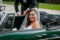 Bride pictured smiling at the camera sitting in a dark green cabriolet in Kenmare.