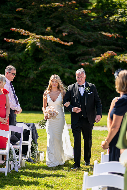 father of the bride and the bride walk down the aisle set in the grounds of the dunloe hotel killarney