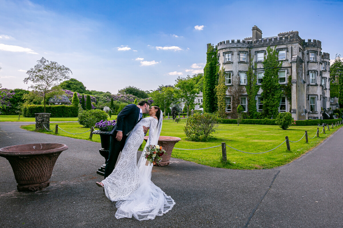 The groom is seen dipping his bride and sharing a tender kiss, Ballyseede castle and its beautiful gardens can be seen in the background.
