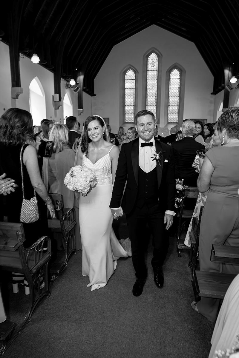 Black and white portrait of bride and groom walking back down the aisle in Kenmare.