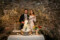 Bride and groom pose behind their wedding cake holding a ceremonial sword to cut the cake at their wedding reception in Ballyseede castle, Tralee.
