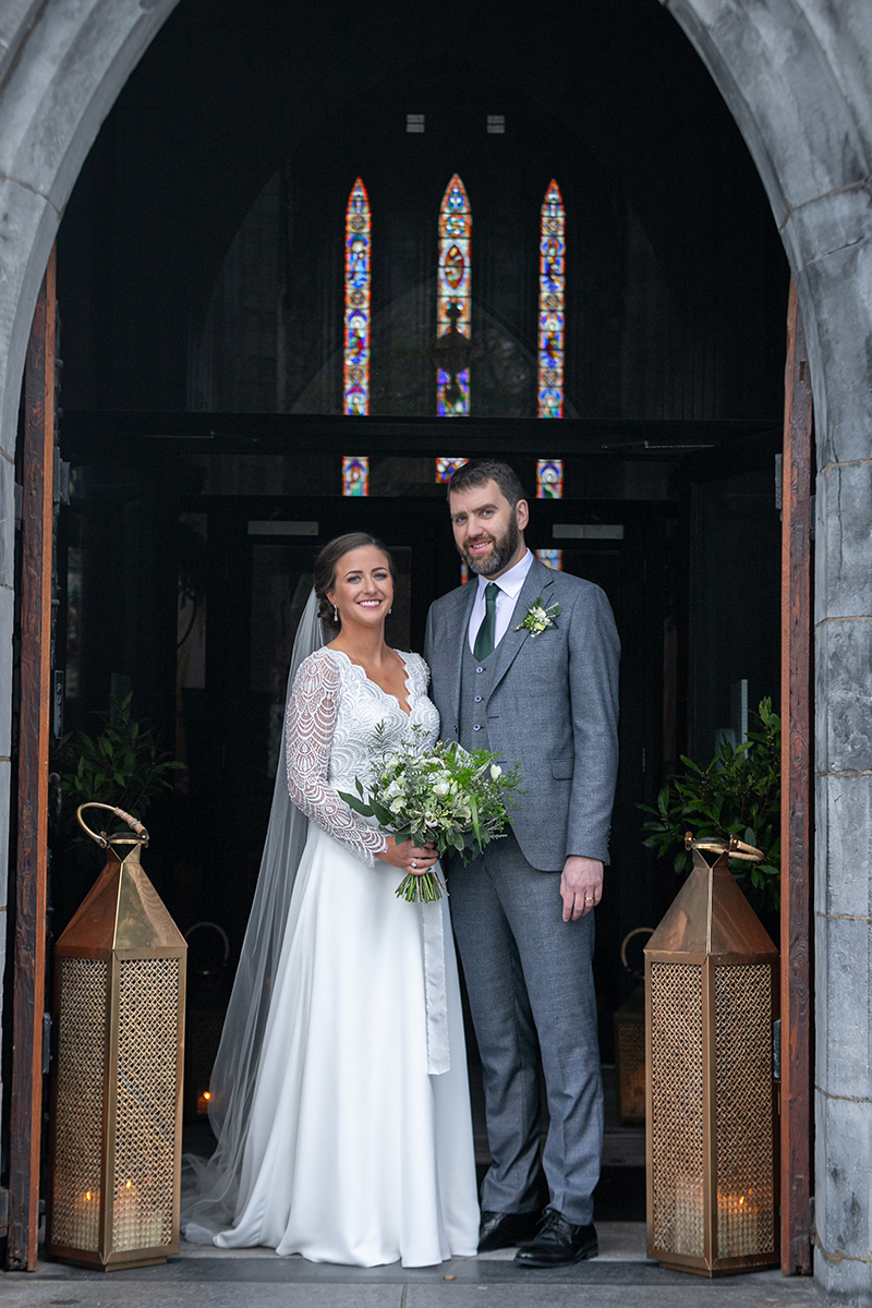 Portrait of the brde and groom stood outside of St Marys Cathedral in Killarney.