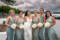 The bride and her bridesmaids smile brightly at the camera, pictured with Kenmare bay in the background and dramatic clouds in the sky.