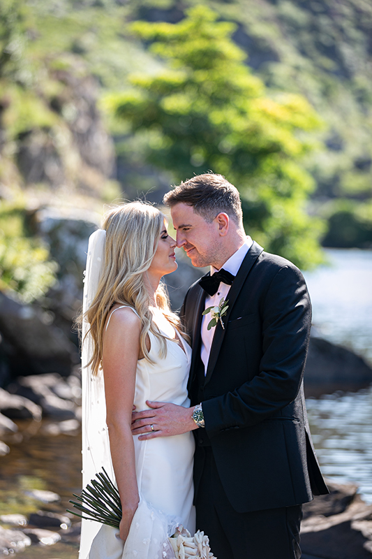 portrait of bride and groom facing one another with a blurry background of the scenery at the gap of dunloe in killarney