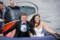 Close up of the bride and groom smiling at the camera, sat at the front of a boat touring the picturesque Kenmare bay.