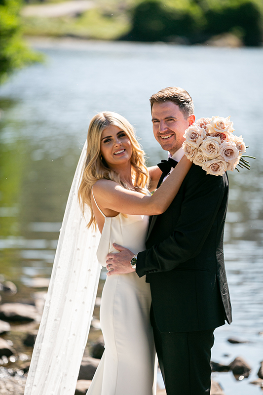 bride and groom embracing and smiling in front of the lake at the gap of dunloe killarney