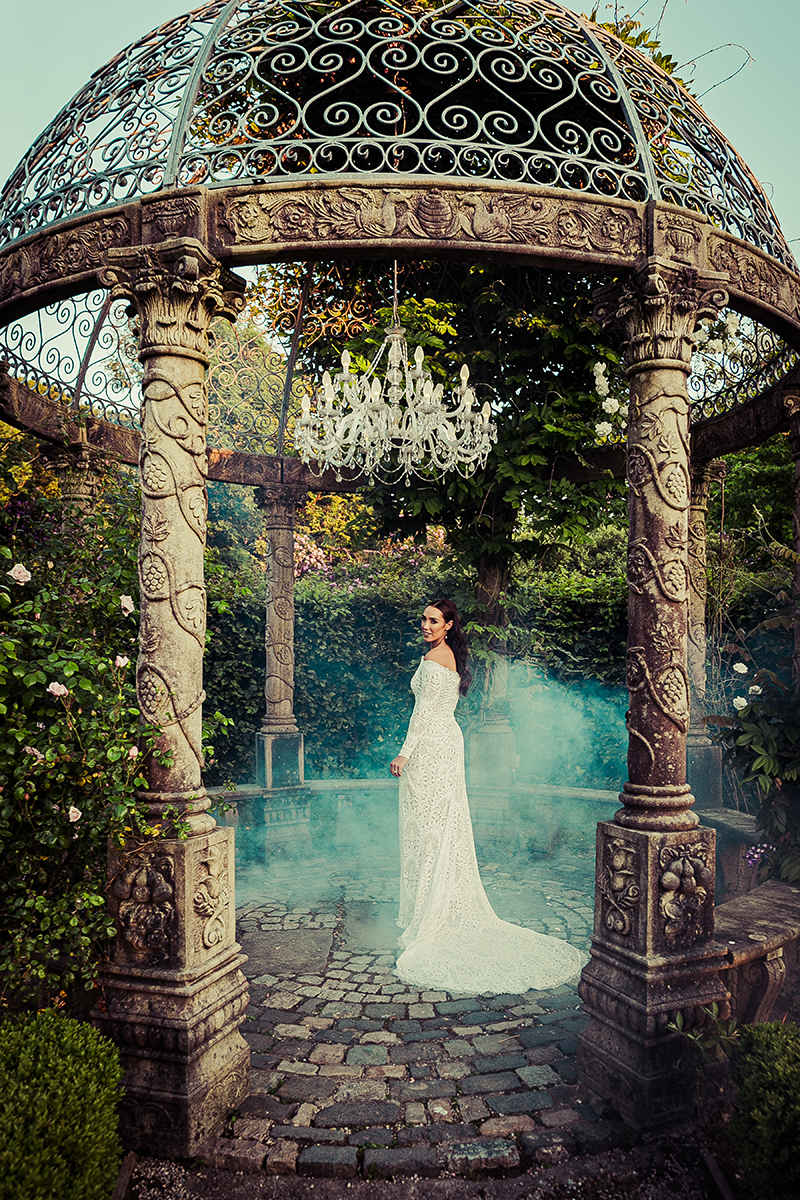 The bride stands in the centre of the round stone gazebo with soft smoke behind her at Ballyseede castle hotel, Tralee.