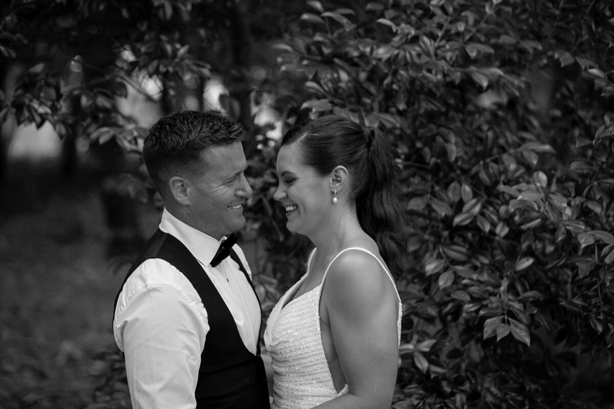 Black and white photograph of bride and groom smiling at one another in the grounds of the Dromquinna Manor.