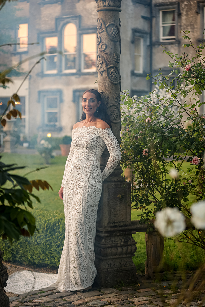 Portrait of the bride leaning against a stone gazebo pillar with Ballyseede hotel visible in the background.