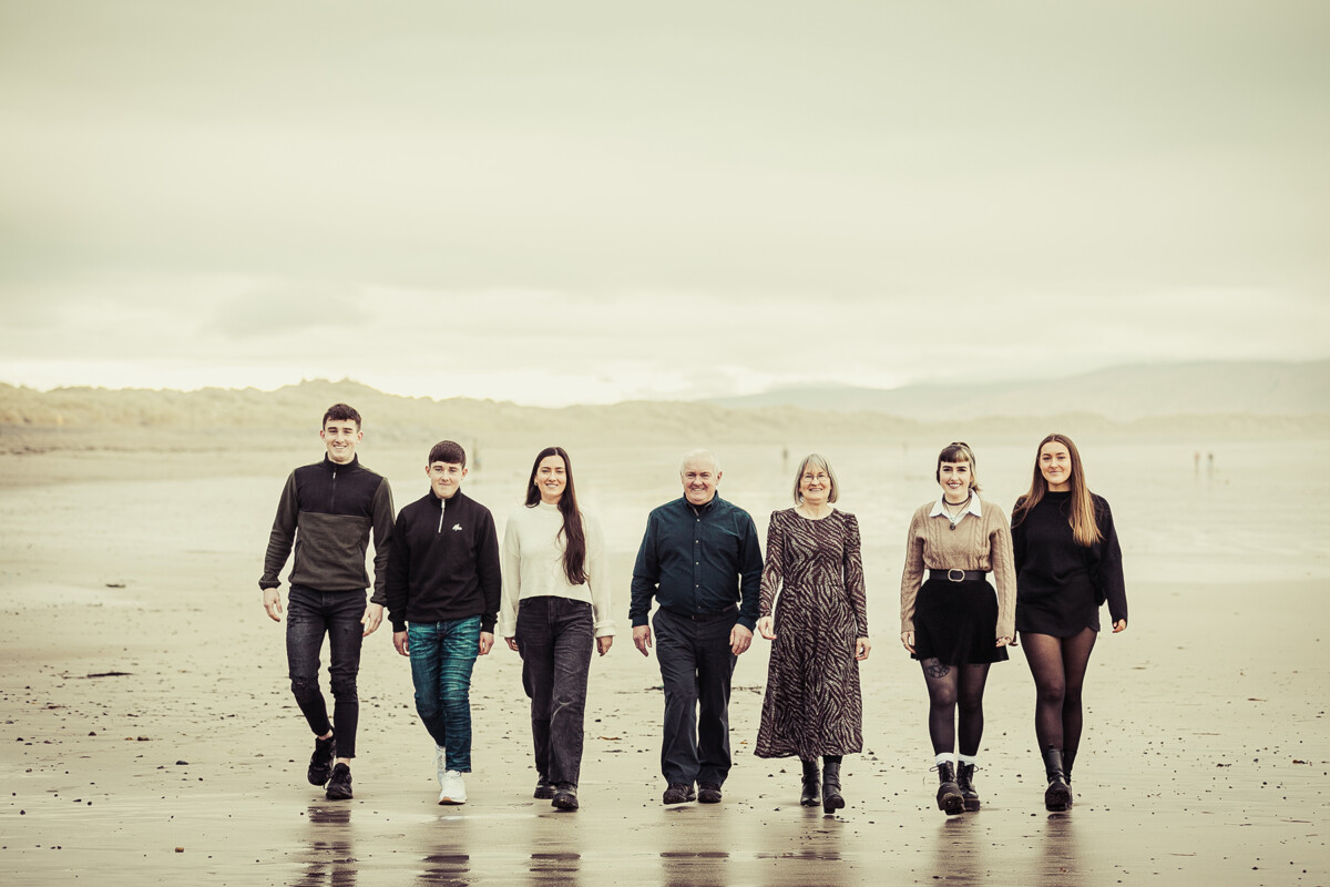 beach portrait of family of 7 walking on ballyheighue beach with the dunes in the background