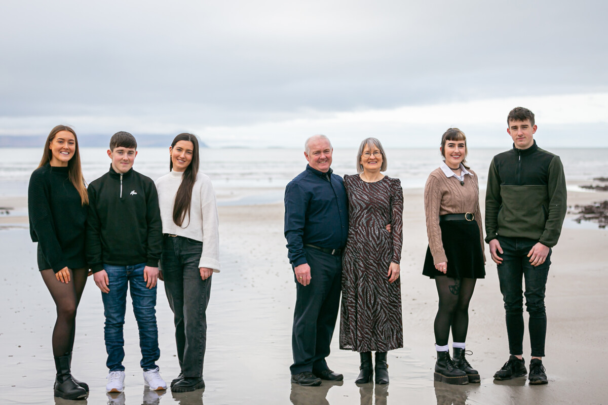 beach portrait of family of 7 standing on the sand on ballyheighue beach with the sea in the background