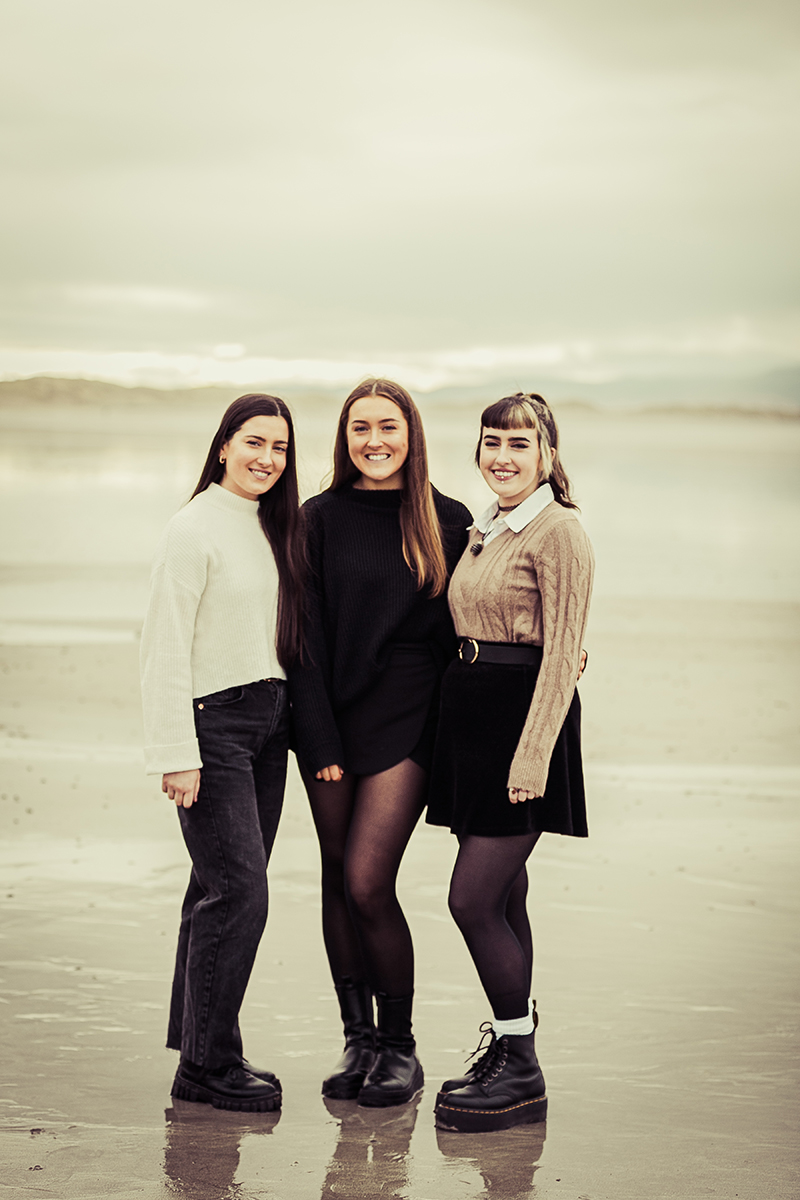 beach portrait of three sisters standing on the sand on ballyheighue beach with soft background