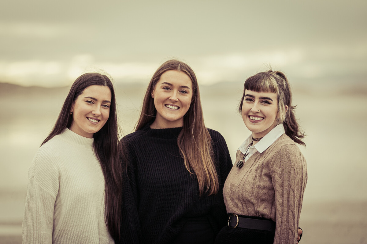 close up beach portrait of three sisters smiling set on ballyheigue beach county kerry with a soft blurred back ground