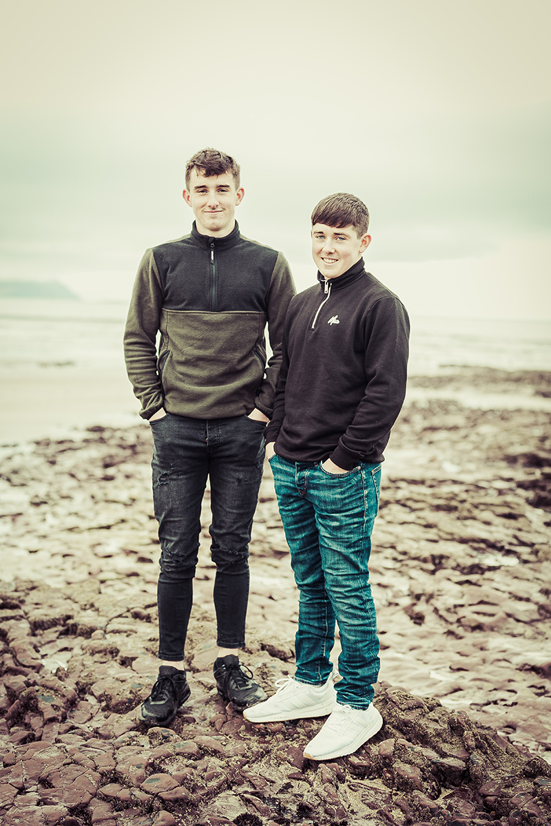 beach portrait of two brothers standing on some rocks on ballyheigue beach in county kerry