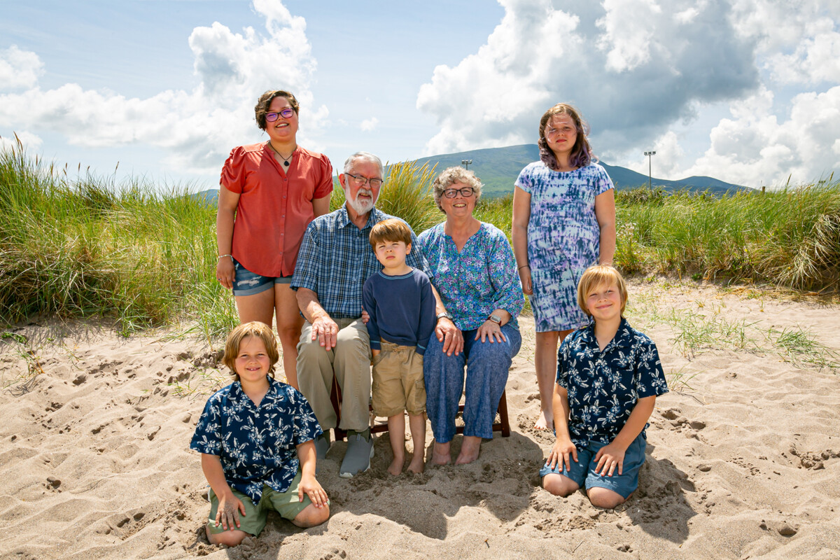 Family beach portrait on a beach in county kerry with blue sky and mountains in background.