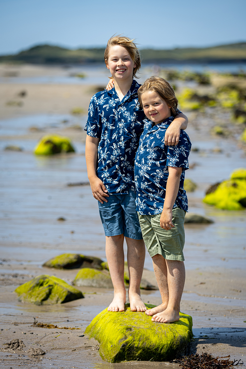 Family beach portrait of two brothers standing on a rock on a beach in County Kerry.