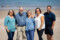 Beach portrait of family standing on the sand on a beach in Castlegregory with the sea in the background.