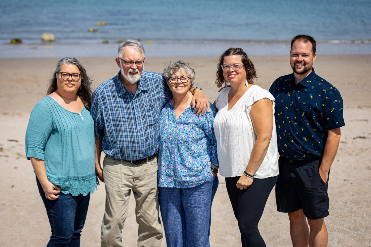 Beach portrait of family standing on the sand on a beach in Castlegregory with the sea in the background.