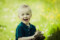 Close up portrait of a little boy laughing and playing with grass with a soft bokeh background.