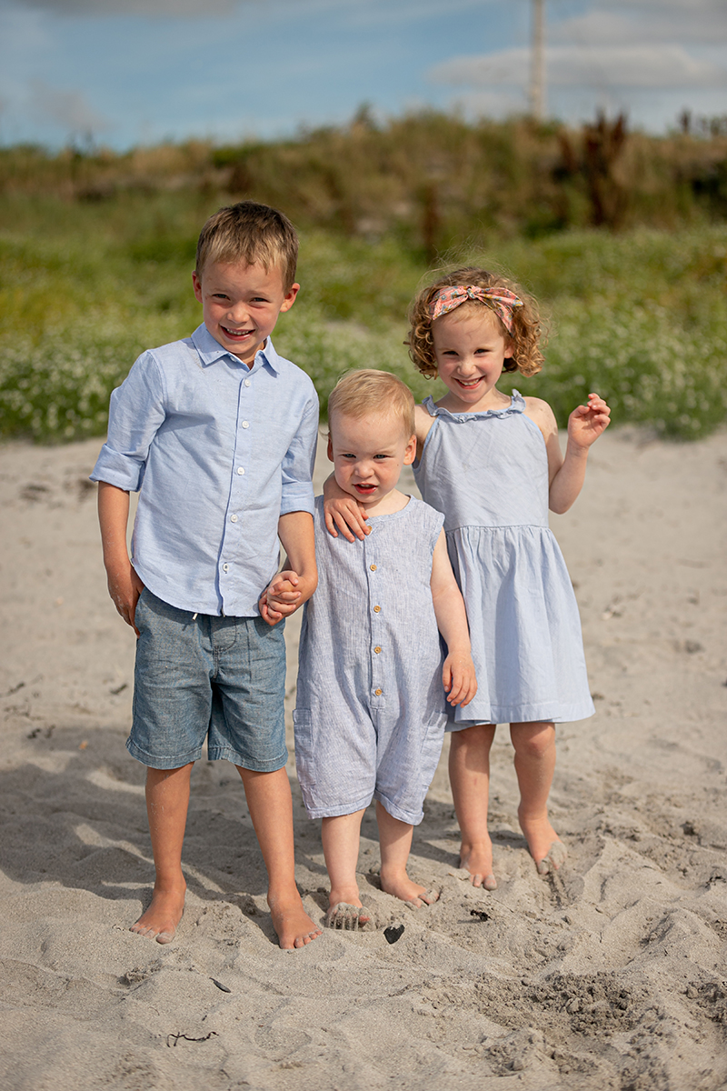 beach portrait of three young siblings stood in the sand at fenit beach