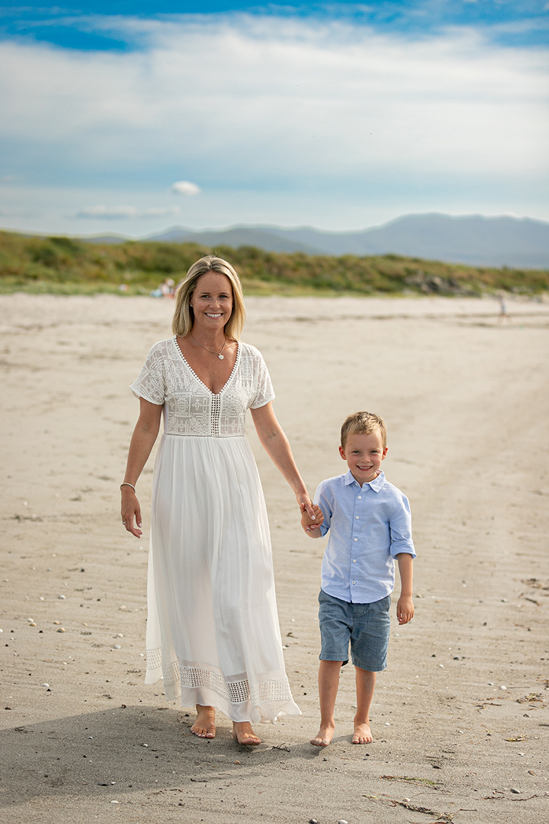 beach portrait of mother and son facing the camera at fenit beach with dunes and blue sky in background
