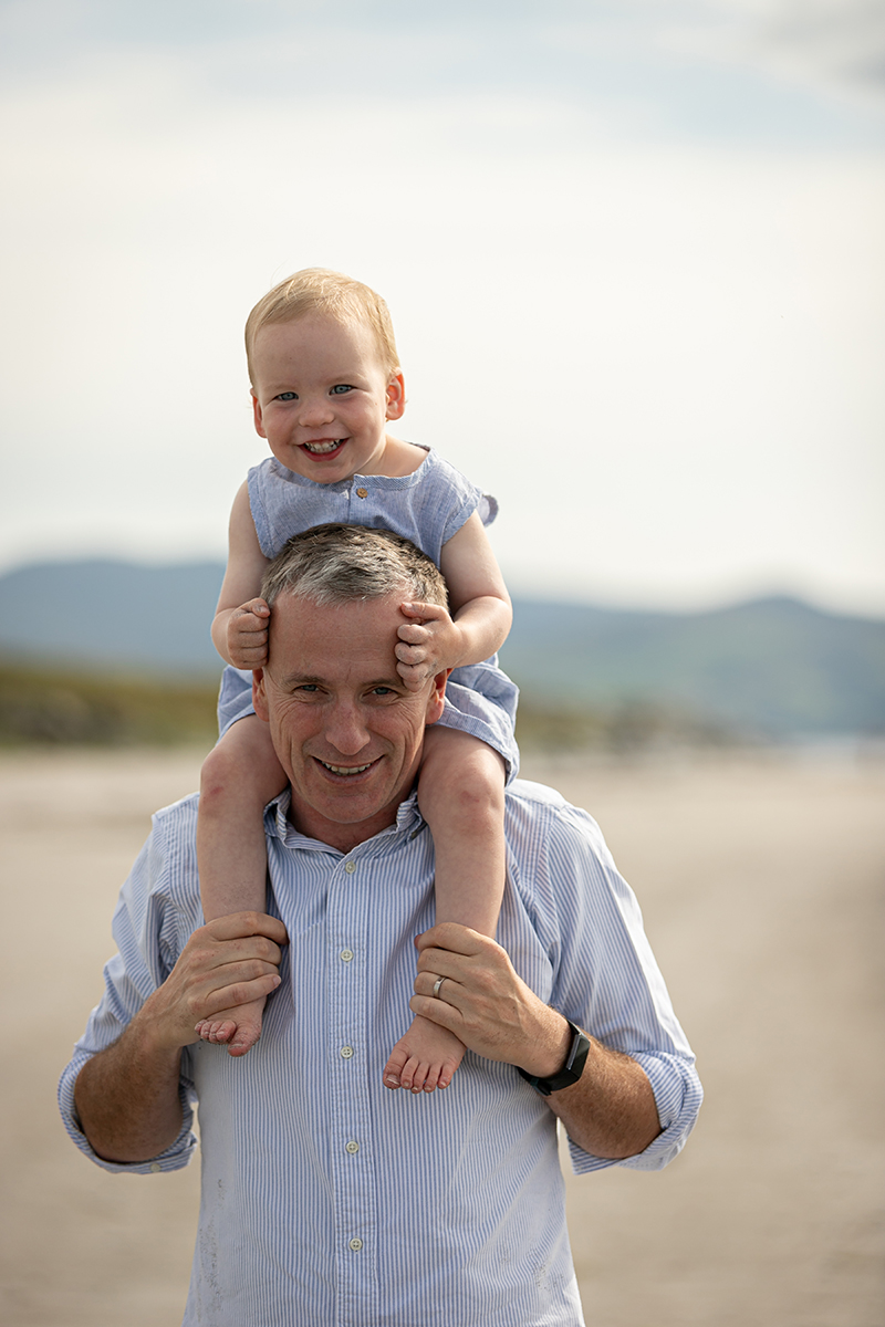 beach portrait of father carrying son on shoulders at fenit beach