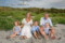 beach portrait of family of 5 sitting in the sand at fenit beach with dramatic sky