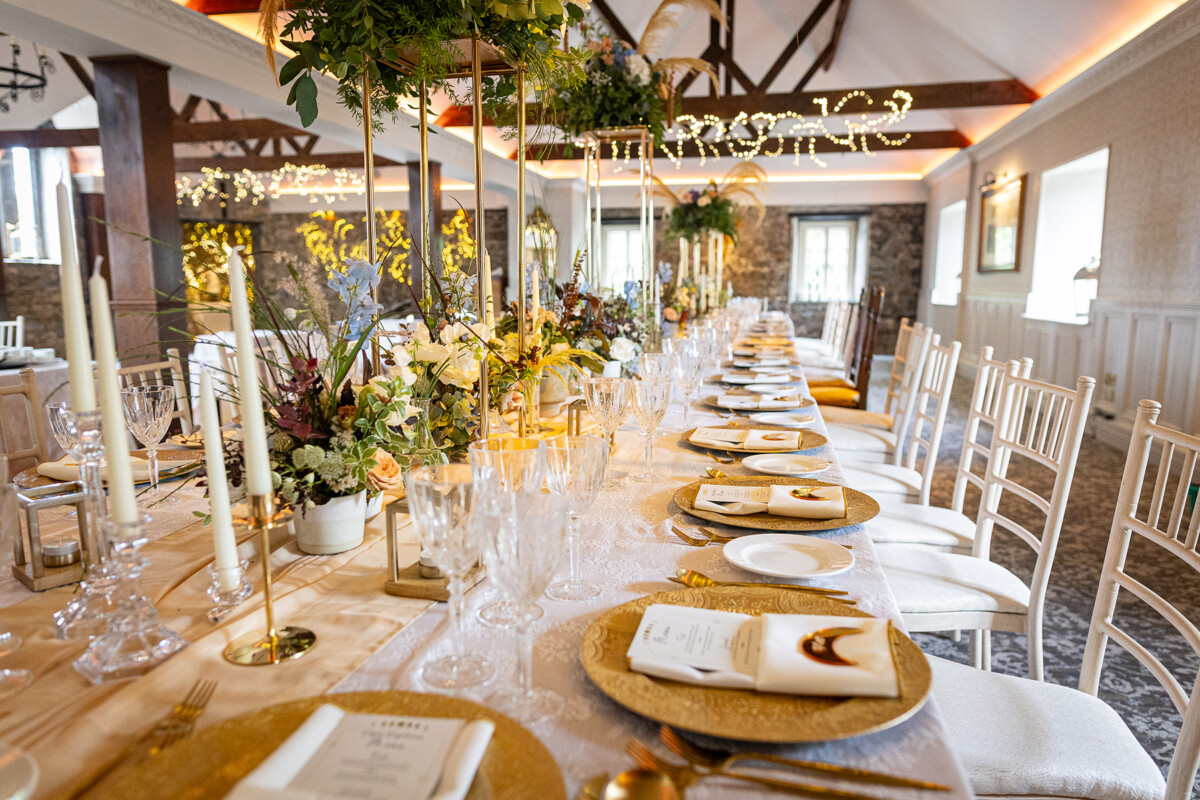 The dining hall at Ballyseede castle is decked out beautifully for a vow renewal with glassware and golden plates lining the table accented by pretty florals.