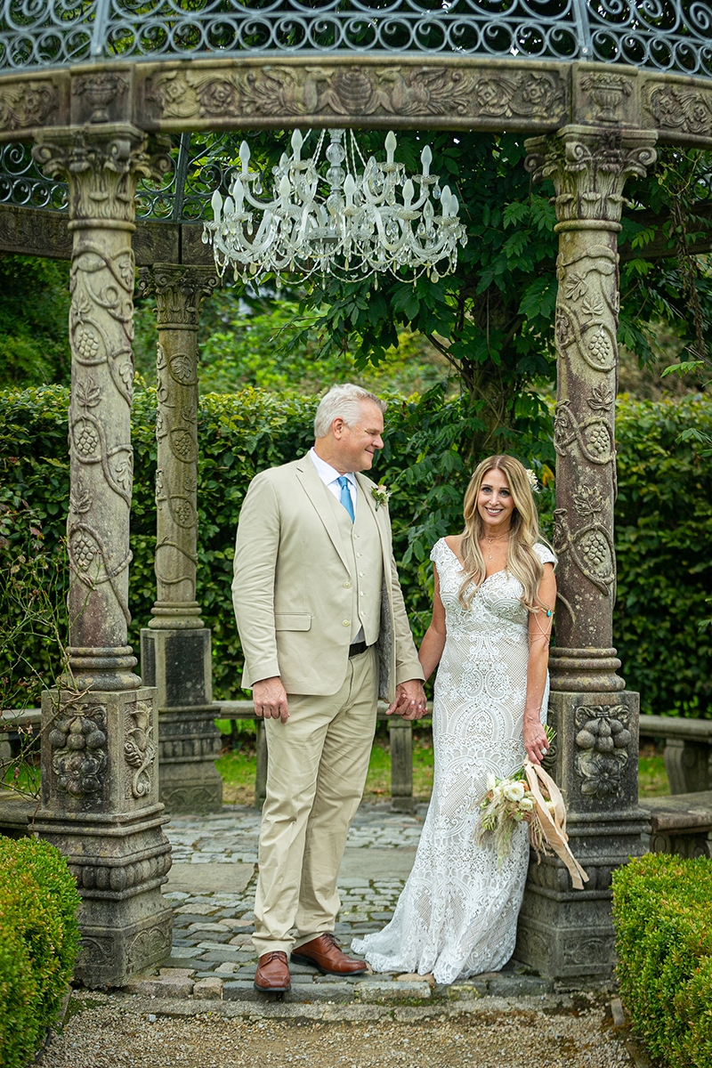 Portrait of husband and wife leaning against a pillar of the stone gazebo at Ballyseede castle, Tralee.