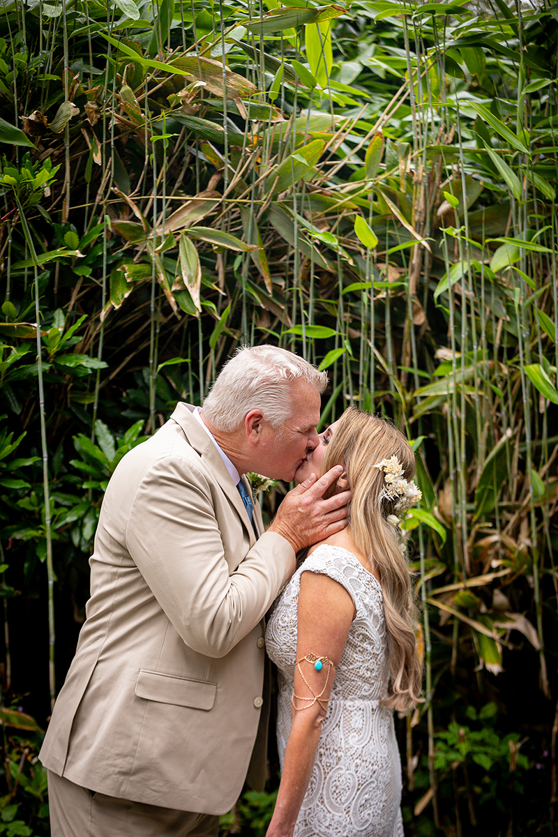 Husband and wife share a kiss in front of the green bamboo on the grounds of Ballyseede castle.